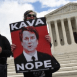 A person holding up a sign with a picture of brett kavanaugh.