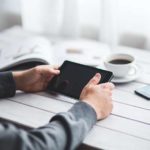 A person is holding an ipad on the table