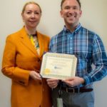 A man and woman holding an award.