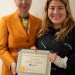 A woman holding an award and standing next to another person.