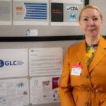 A woman in an orange suit standing next to some posters