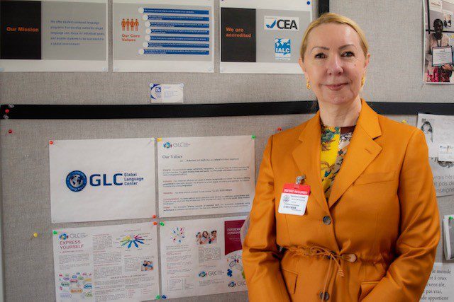 A woman in an orange suit standing next to some posters